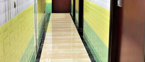 A hallway with tiled walls, a marble floor, and doors with a sign indicating a no-smoking area.