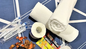 A collection of personal care items including a rolled-up towel, toothbrushes, toothpaste, a pack of Nescafe coffee, a woven ball, dried orange peels, and a pair of earplugs. - I Top Guest House (Kowloon)