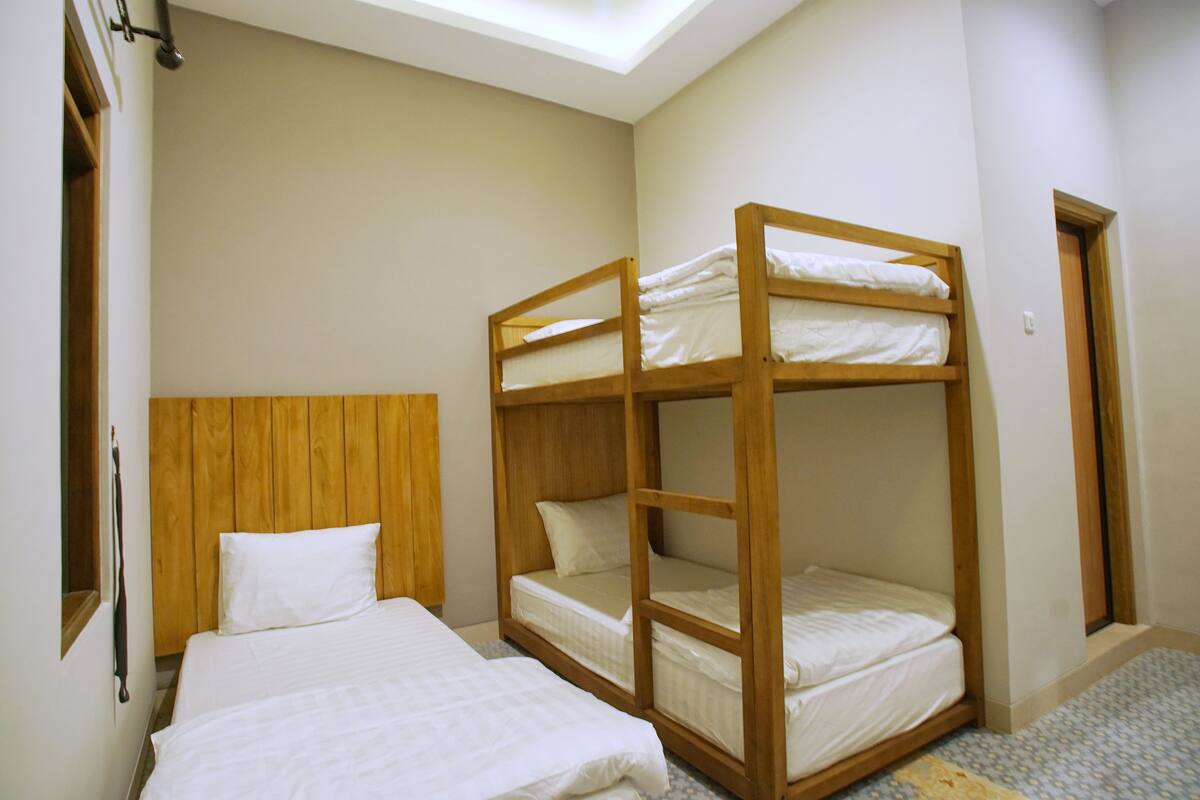 Een kamer met stapelbedden, een houten hoofdbord en een dakraam.