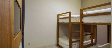 A room with bunk beds, a wooden wardrobe, and a small table with a tissue box.