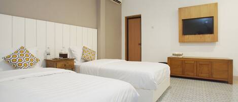 A hotel room with two beds, a TV mounted on the wall, a wooden cabinet, and patterned floor tiles.