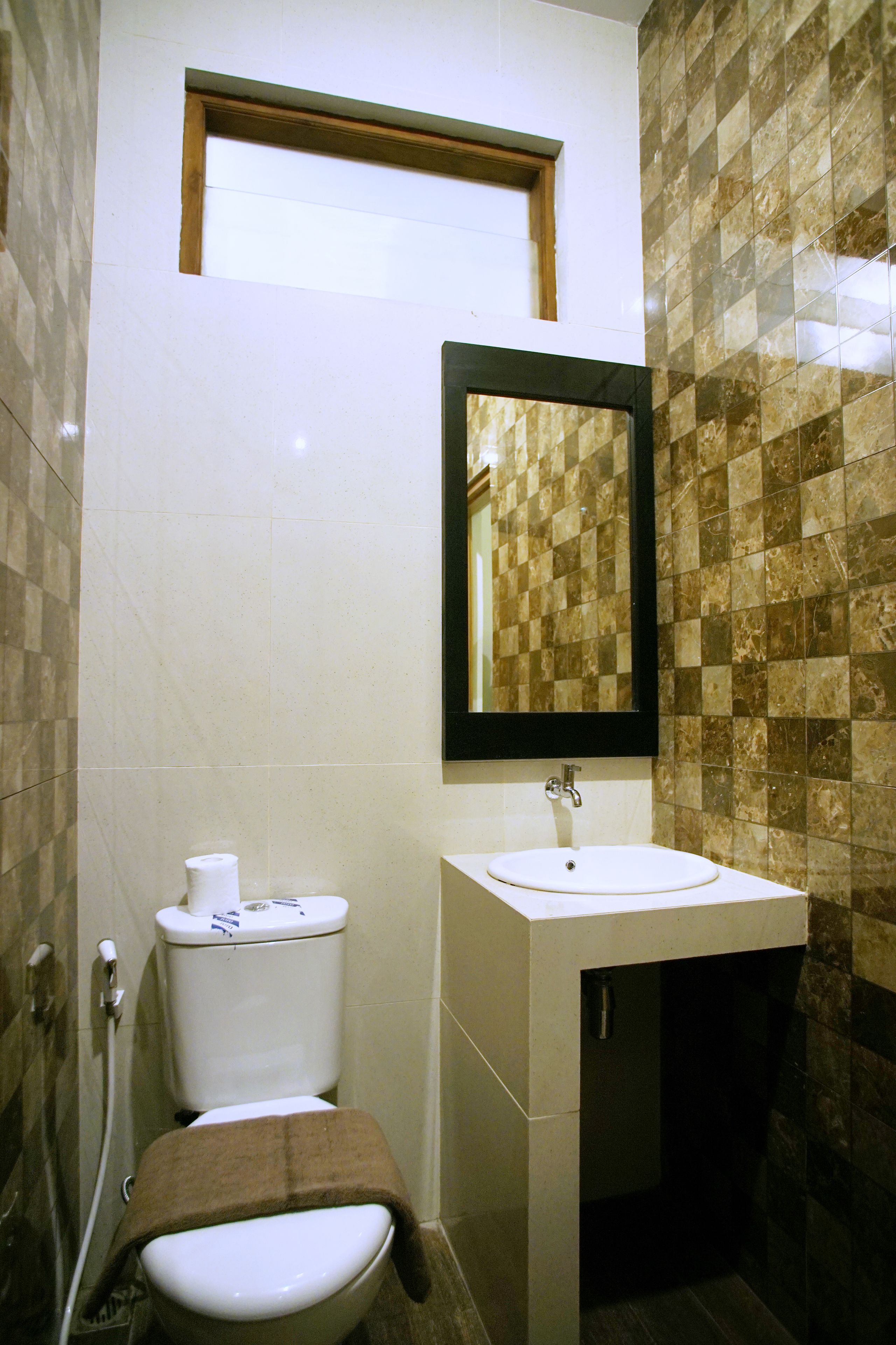 Un baño con inodoro, lavamanos y espejo.