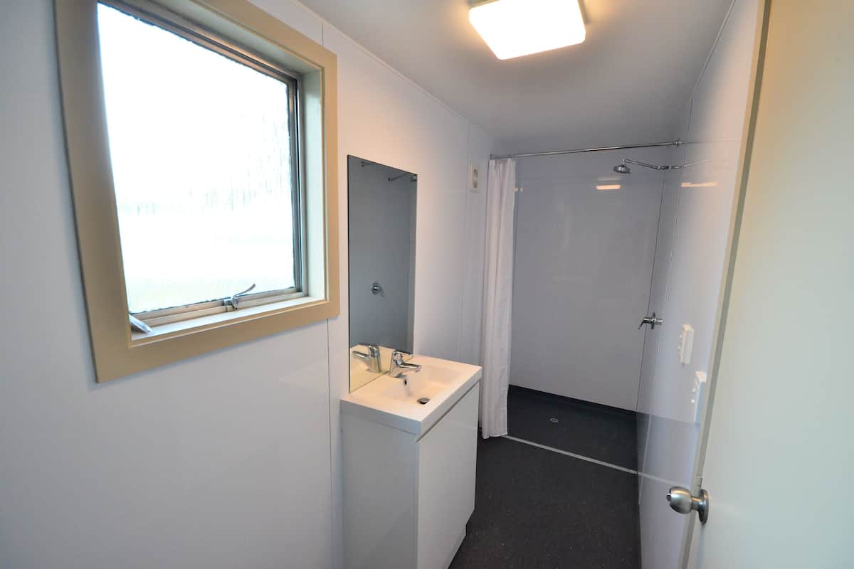 Une petite salle de bain avec une fenêtre, un lavabo et une douche.