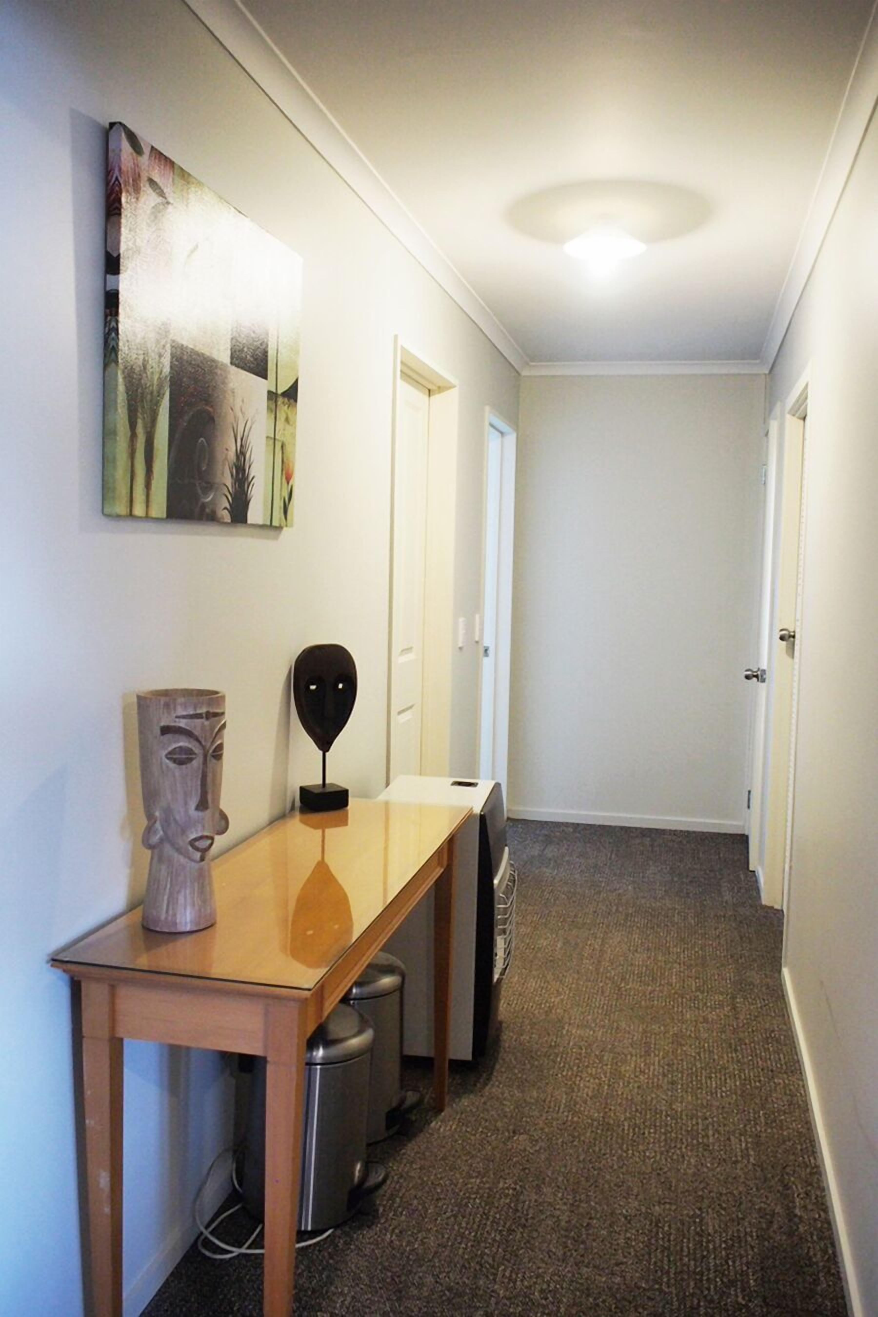 Un pasillo con una mesa de madera, una escultura y un cuadro en la pared.
