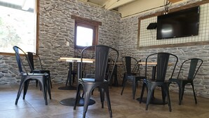 Ein Restaurantinneres mit Steinwänden, einem Holztisch und schwarzen Stühlen.