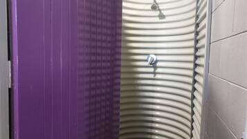 A bathroom with a purple door, a white sink with a curved basin, and a white tiled wall.