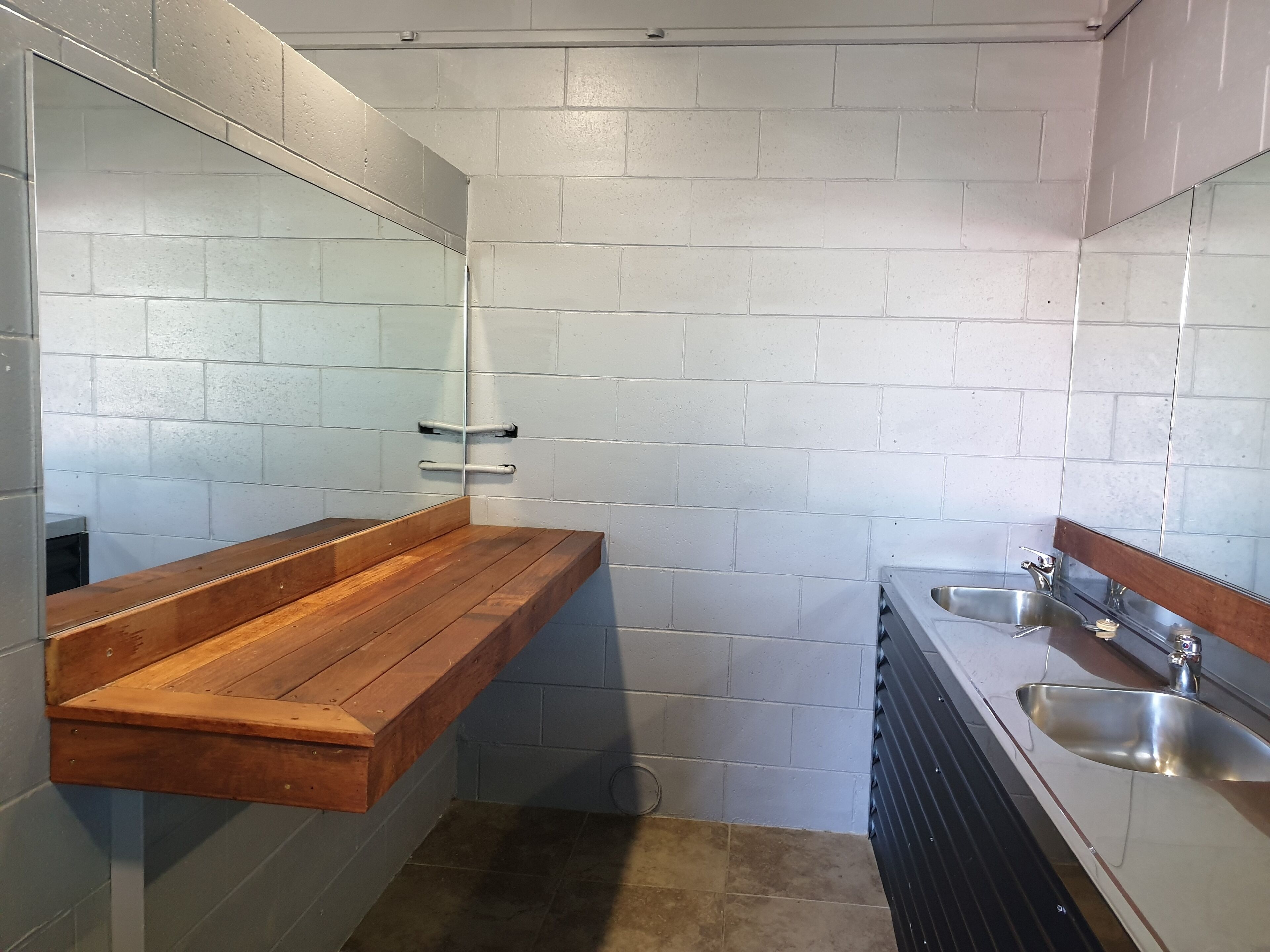 Een compacte, moderne badkamer met een houten wastafelmeubel, een wastafel en een spiegel.