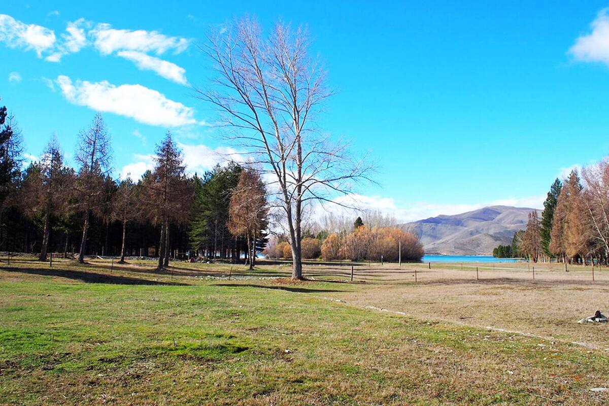 Un parc avec un ciel dégagé, un lac et des montagnes en arrière-plan.