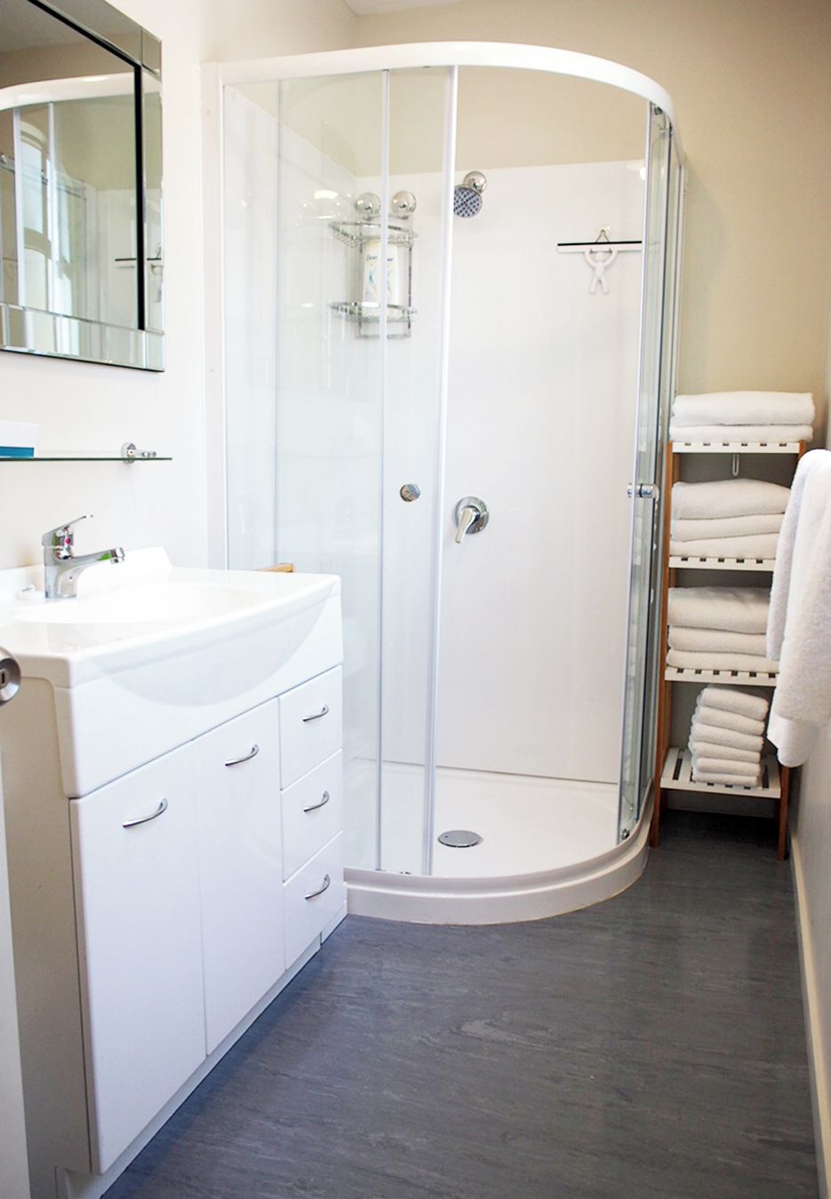 Un bagno moderno con cabina doccia in vetro, lavandino bianco e porta asciugamani.
