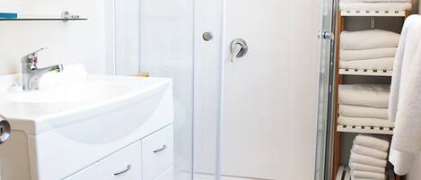 A modern bathroom with a glass-enclosed shower, a white sink, and a towel rack.