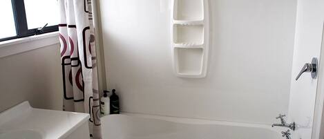 A bathroom with a bathtub, a sink, and a shower curtain.
