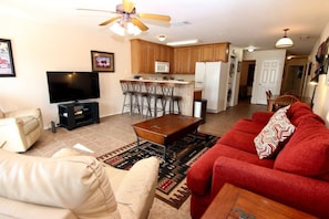 Relax in this open-plan living space with a kitchen area, featuring a sofa, coffee table, and television.