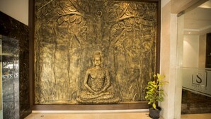 Una estatua de Buda en posición meditativa, rodeada por un elaborado diseño de árbol.