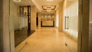 Zona de recepción de un hotel con diseño moderno, que incluye un mostrador de recepción, separadores de vidrio e iluminación contemporánea.