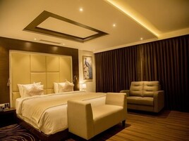 Un dormitorio moderno con una cama grande, un sofá, una silla y un cuadro en la pared.