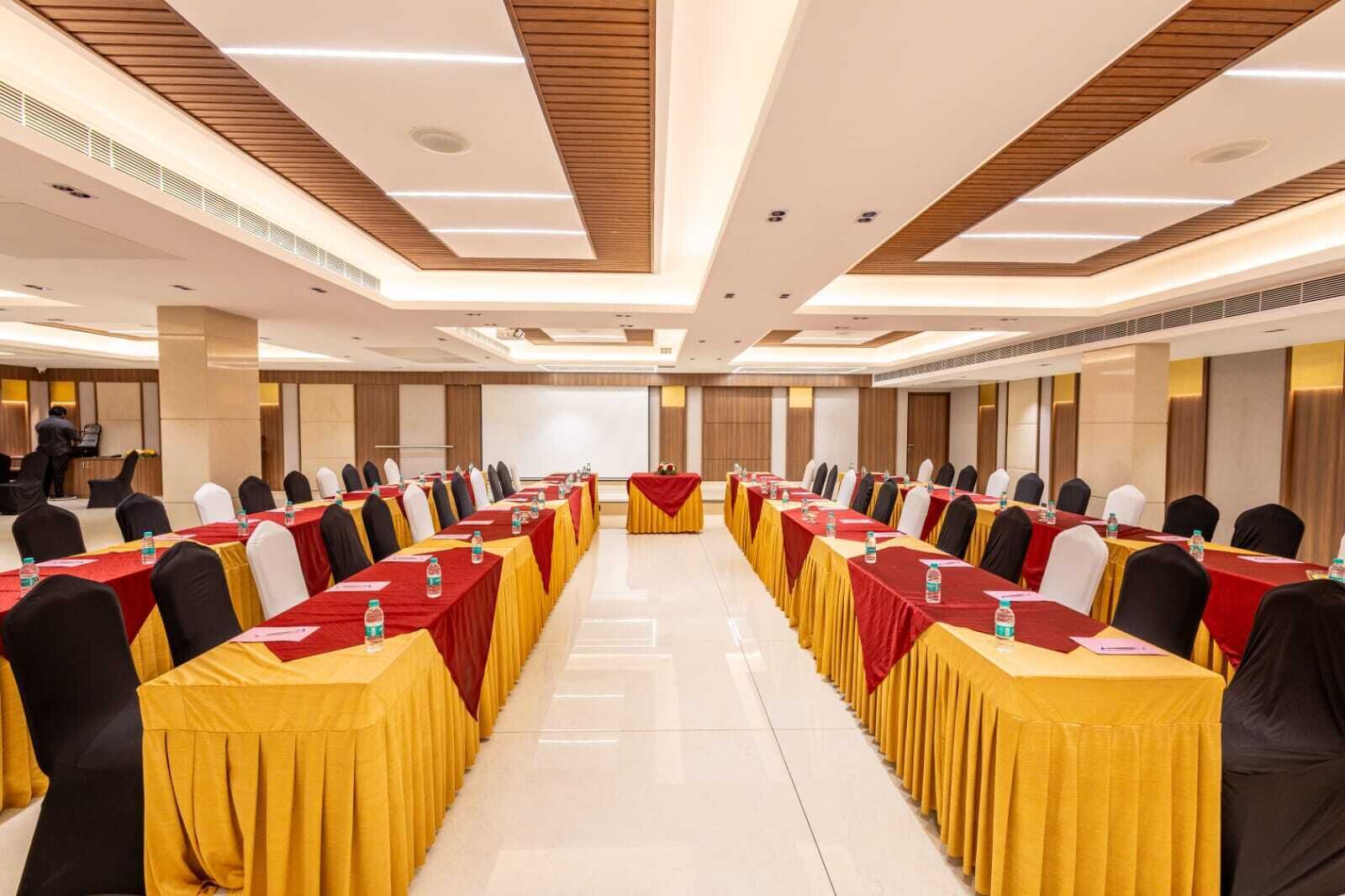 A conference room with rows of tables, chairs, and a podium at the front.