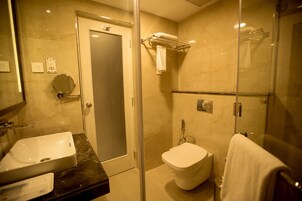 Un baño moderno con cabina de ducha de vidrio, un lavamanos blanco y un inodoro.