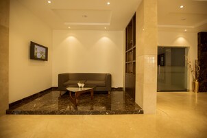 A modern lobby with a marble floor, a grey sofa, and a small table with a bowl.