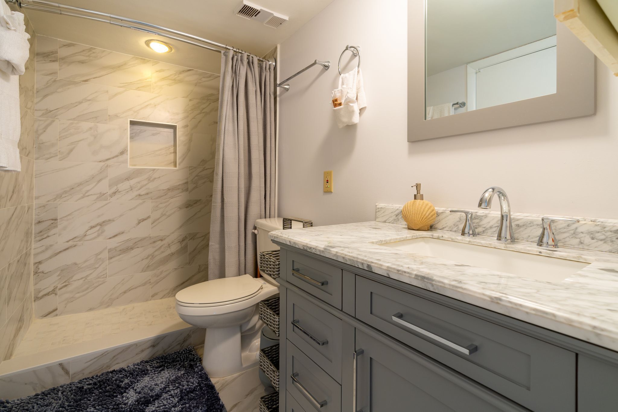 A bathroom with a shower, toilet, and vanity with a sink and mirror.