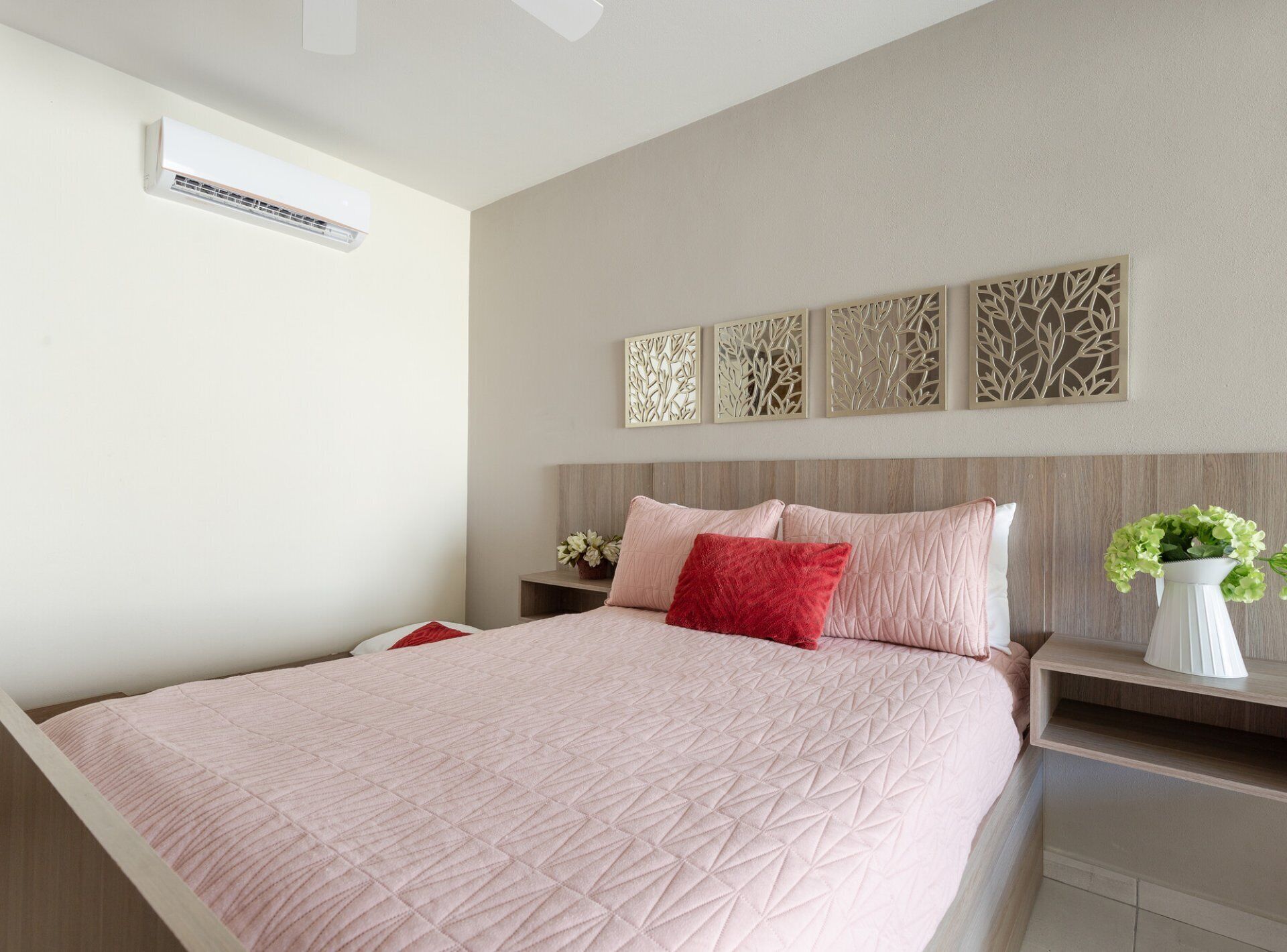 Un dormitorio con una cama grande, una mesita de noche y un aire acondicionado instalado en la pared.