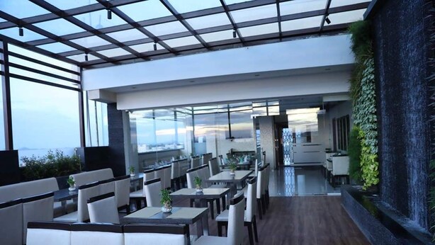 A modern restaurant with high ceilings, glass partitions, and a view of the cityscape.