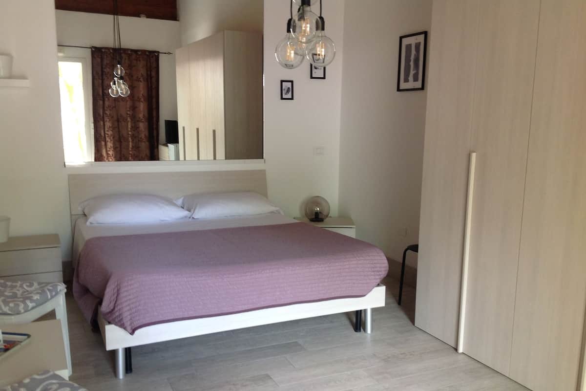 A bedroom with a bed, bedside table, lamp, and a wardrobe.