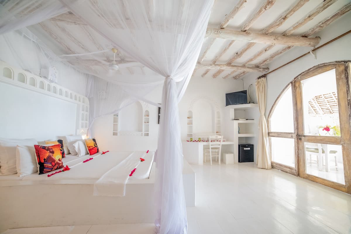 Una habitación amplia con una cama grande, un escritorio y una ventana con vistas.