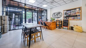A cafe with a wooden table and chairs, a counter with a chalkboard menu, and a wall with various posters and a globe decoration. - MH48 Hotel (Hengchun)