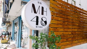 A sign with the letters "MH 48" and some text in another language, mounted on a building with a wooden slat wall. - MH48 Hotel (Hengchun)