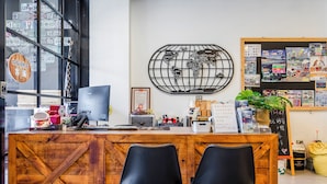 A reception desk with a wooden design, two black chairs, a computer, and various items on the counter. - MH48 Hotel (Hengchun)