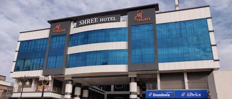 Un moderno edificio de hotel con amplios ventanales y un cartel que dice Shree Hotel.