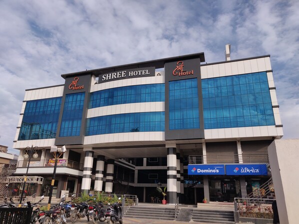 Moderni hotellirakennus, jossa on suuret lasi-ikkunat ja Shree Hotel -kyltti.