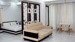 A modern hotel room with a bed, a beige sofa, a small table, and a ceiling fan. - Shree Hotel (Danta)