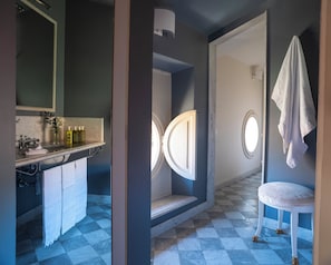 Un baño con encimera de mármol, lavamanos, espejo, toallero y ventana.