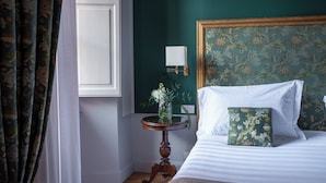 A neatly arranged bedroom with a bed, a bedside table with a vase, and a wall-mounted lamp. - Albergo Pietrasanta (Pietrasanta)