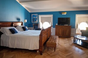 Un dormitorio con una cama de madera, un banco, un aparador, un televisor y una silla.