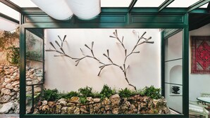 A modern interior space with a glass enclosure, a rock garden, and a wall-mounted branch sculpture. - Albergo Pietrasanta (Pietrasanta)
