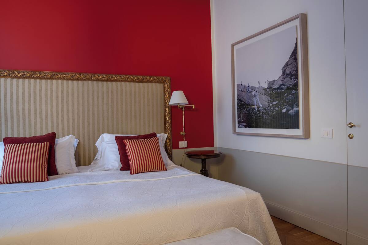A hotel room with a bed, a nightstand, a lamp, and a framed picture on the wall.