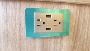 A teal-colored electrical outlet on a wooden wall. - Duo Yuan Hua BB (Chaozhou)