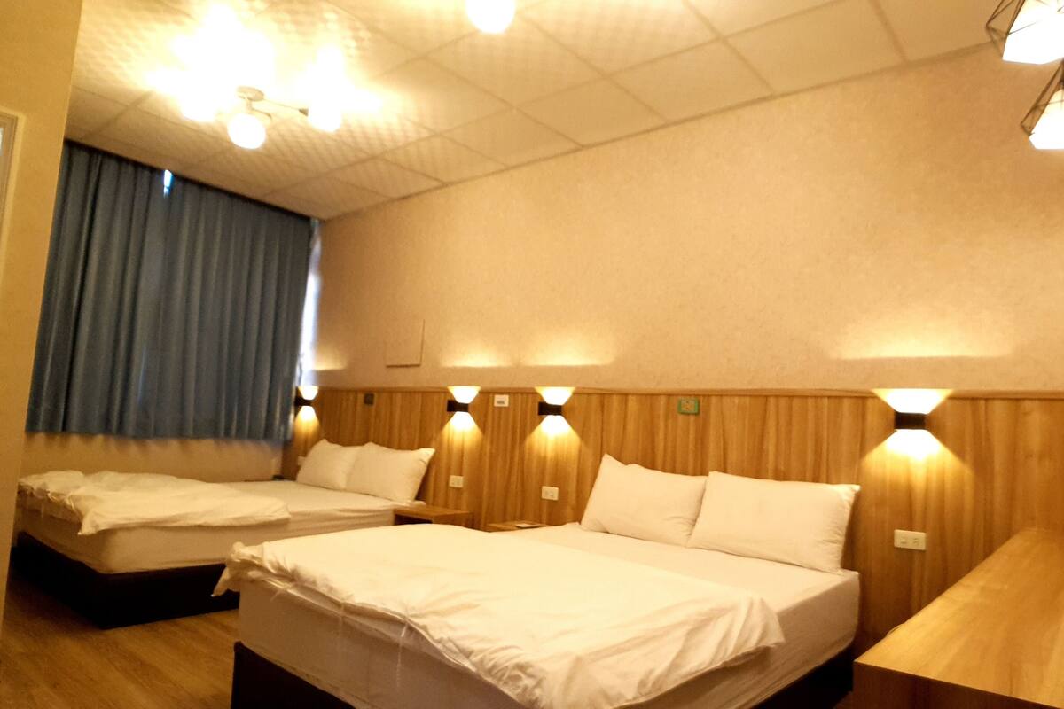 Une chambre d’hôtel avec deux lits, des têtes de lit en bois et des lampes fixées au mur.