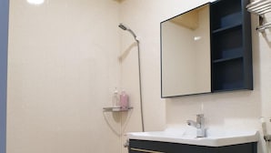 A bathroom with a shower, a sink with a mirror, and a toilet. - Duo Yuan Hua BB (Chaozhou)