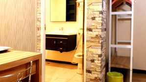 A room with a stone accent wall, a wooden desk, a chair, a mirror, and a white wardrobe. - Duo Yuan Hua BB (Chaozhou)