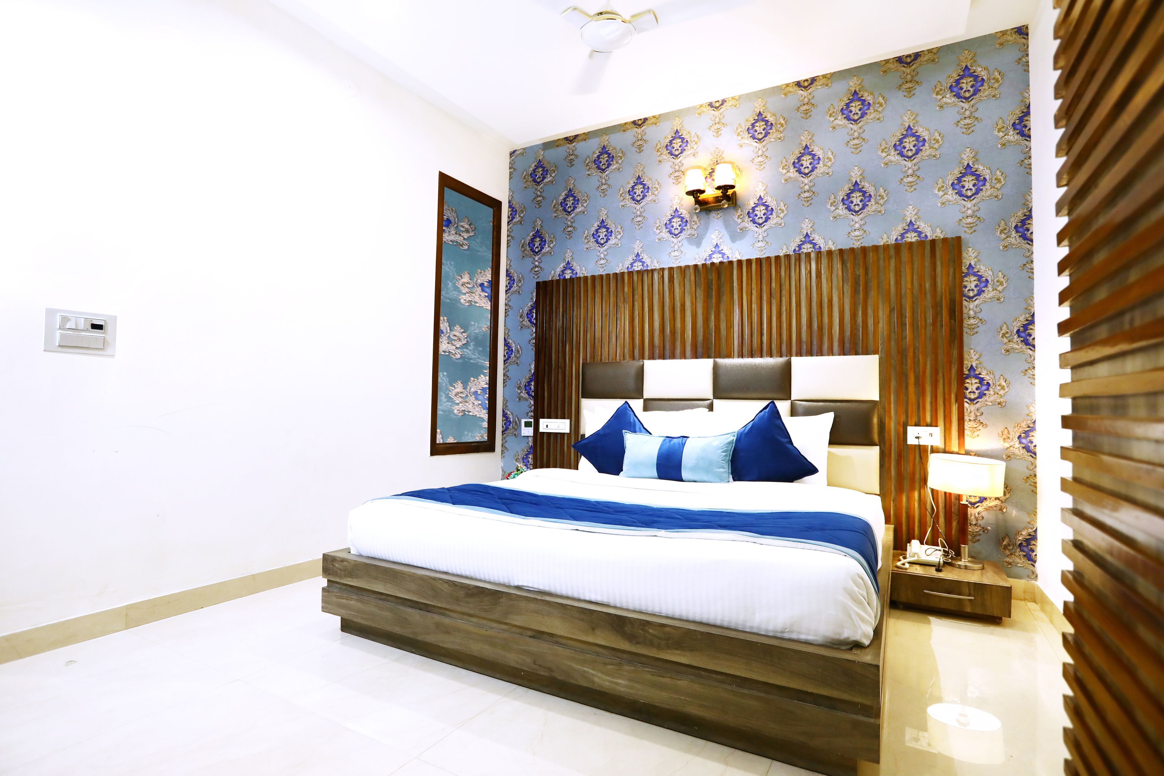 A neatly arranged bedroom with a bed, bedside table, and a wall-mounted light fixture.