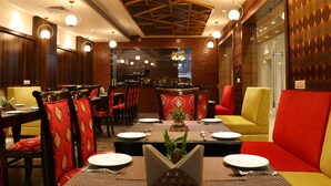 A restaurant with wooden walls, red and yellow seating, and a central dining table with place settings.