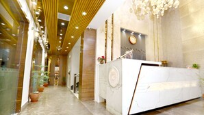 A modern reception area with a marble counter, potted plants, and a decorative wall clock.