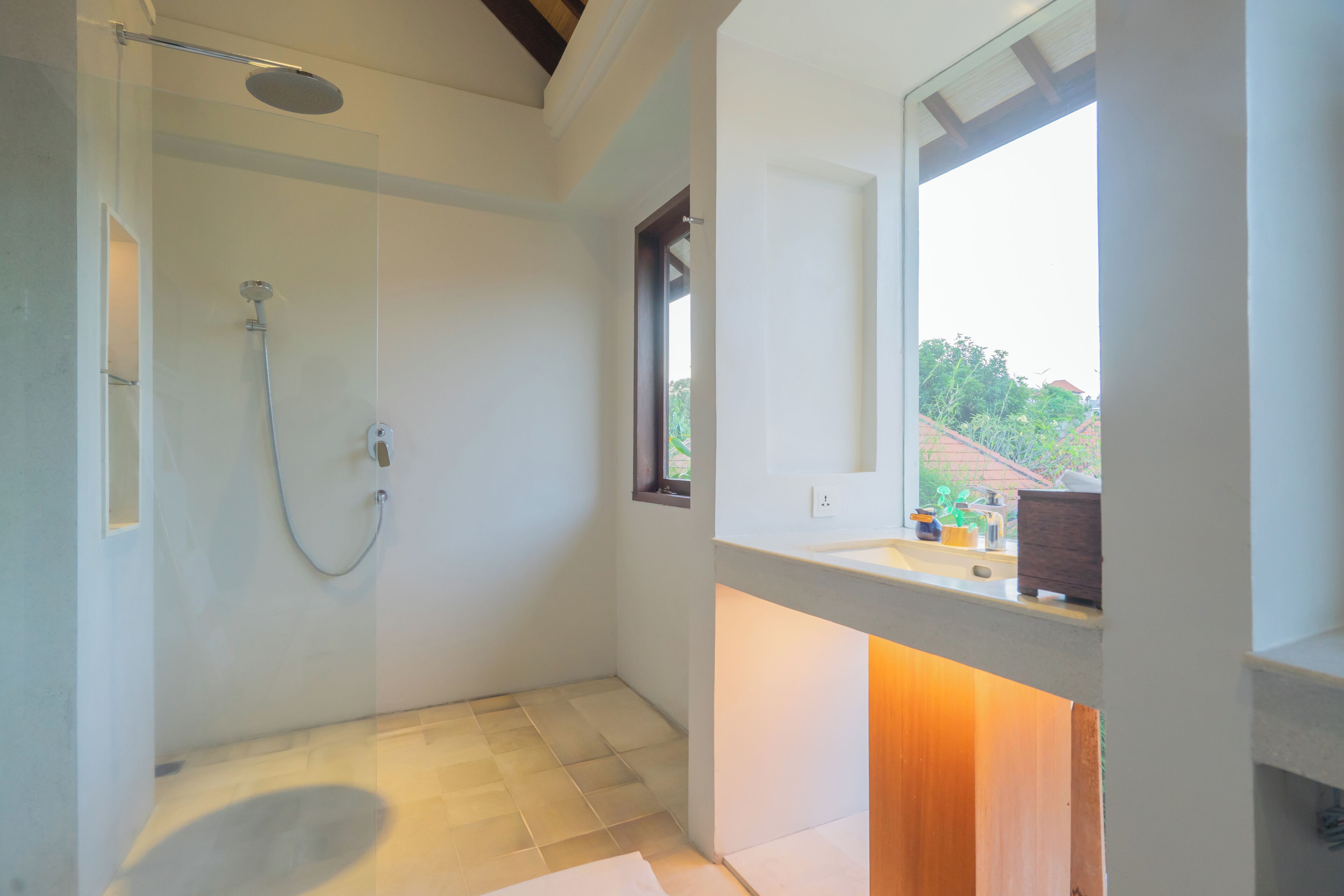 A modern bathroom with a shower, a sink, and a window providing a view of the outdoors.