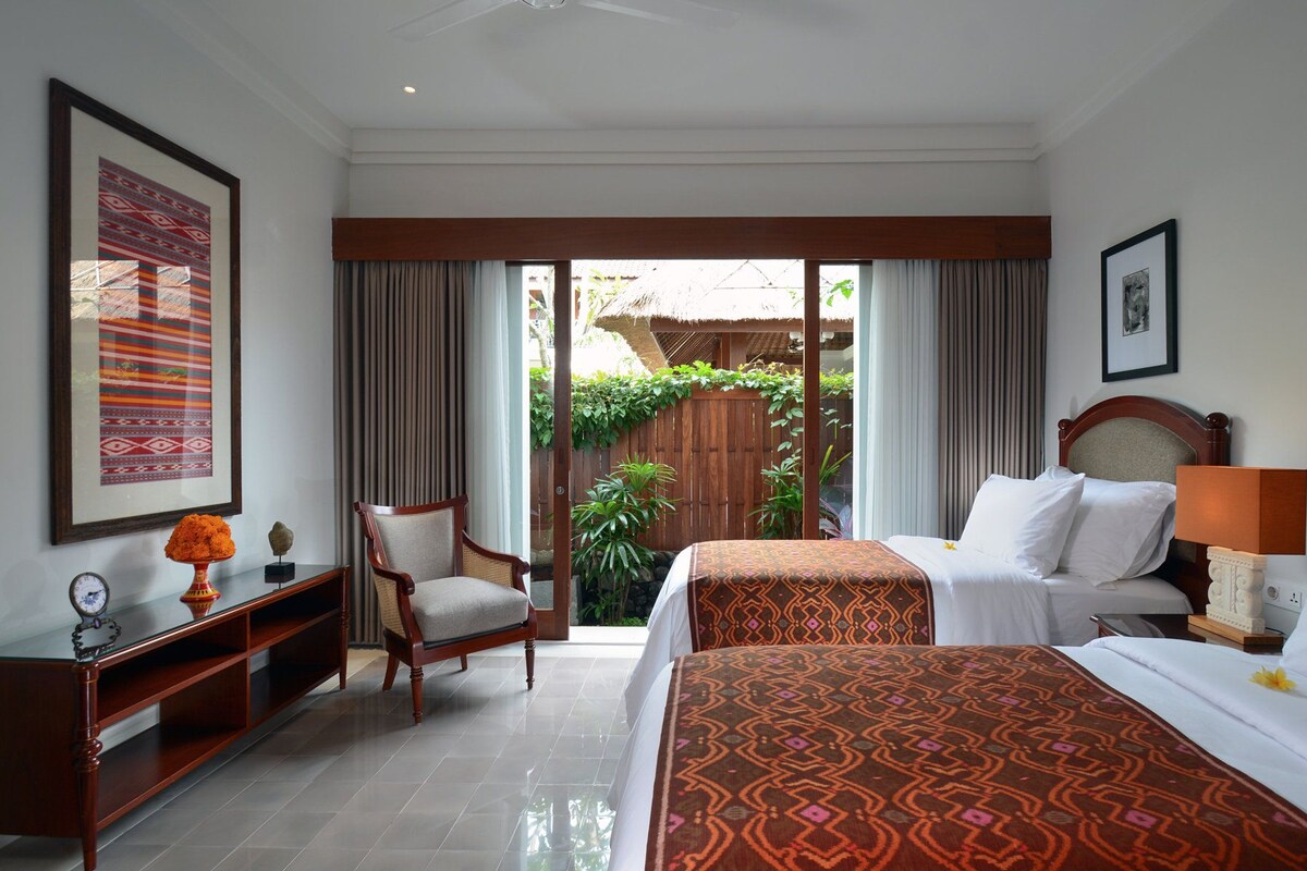 A hotel room with a bed, a chair, a desk, and a view of the outside.