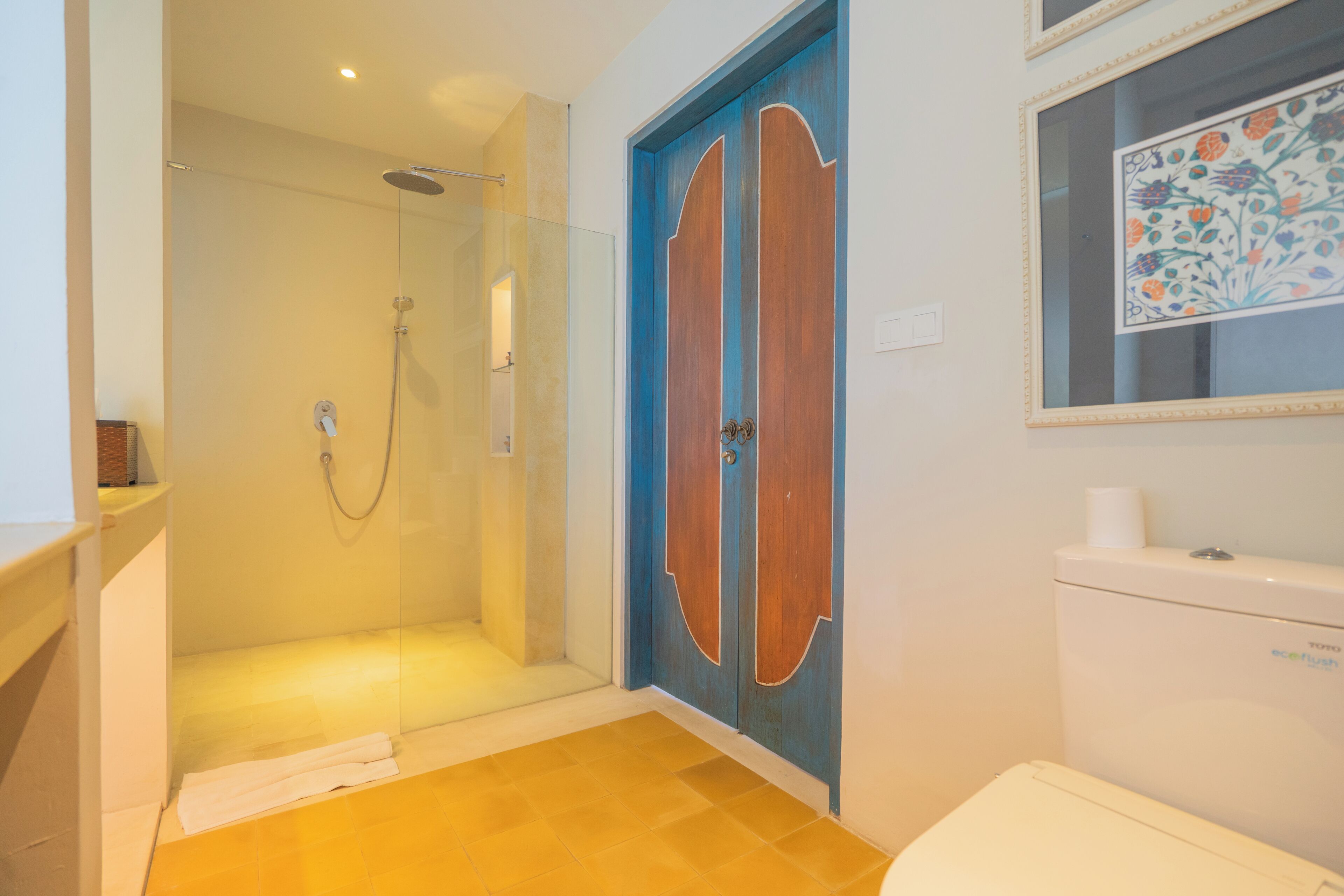 A bathroom with a glass-enclosed shower, a toilet, and a decorative door.