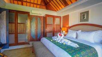 Quarto de hotel com cama, um banco, guarda-roupa e teto com vigas de madeira.
