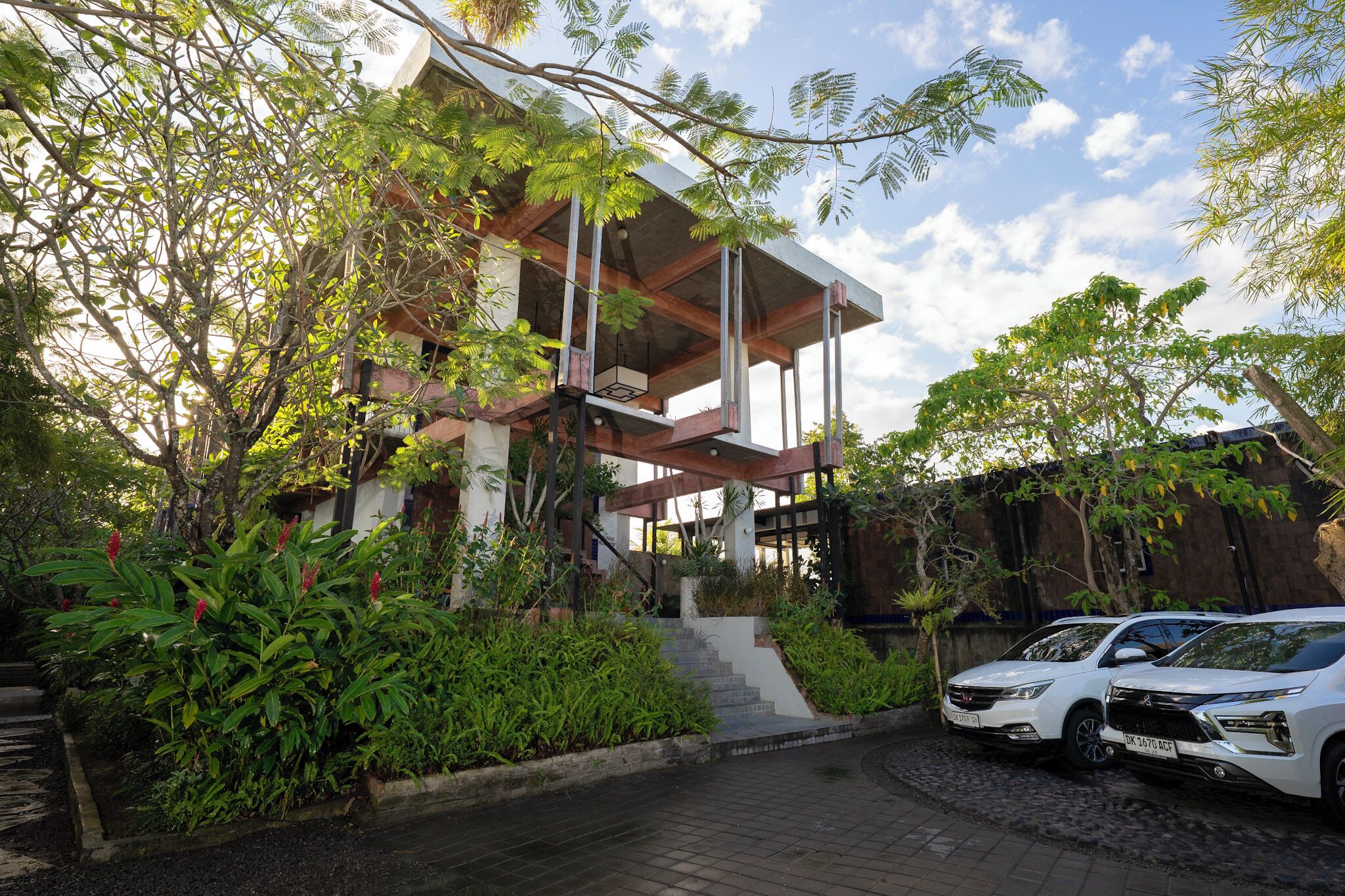 Uma casa moderna com escadaria para uma varanda, rodeada por vegetação exuberante.